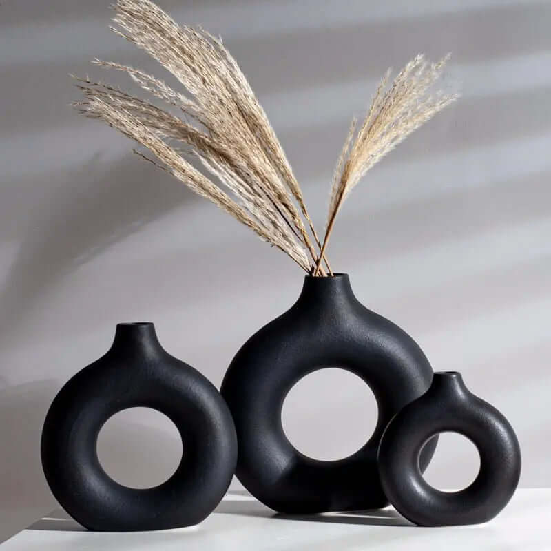 Collection of three black vases with decorative pampas grass