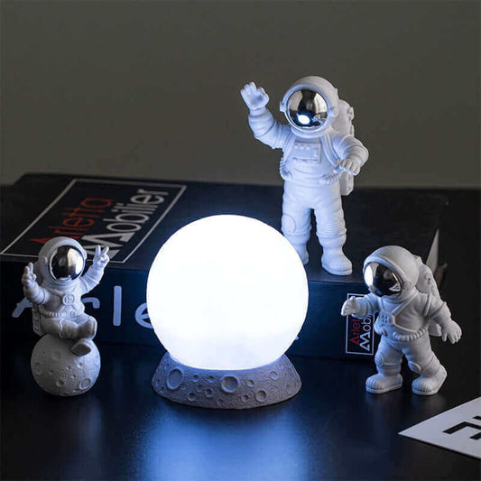 Astronaut figurines displayed on a table alongside a glowing globe